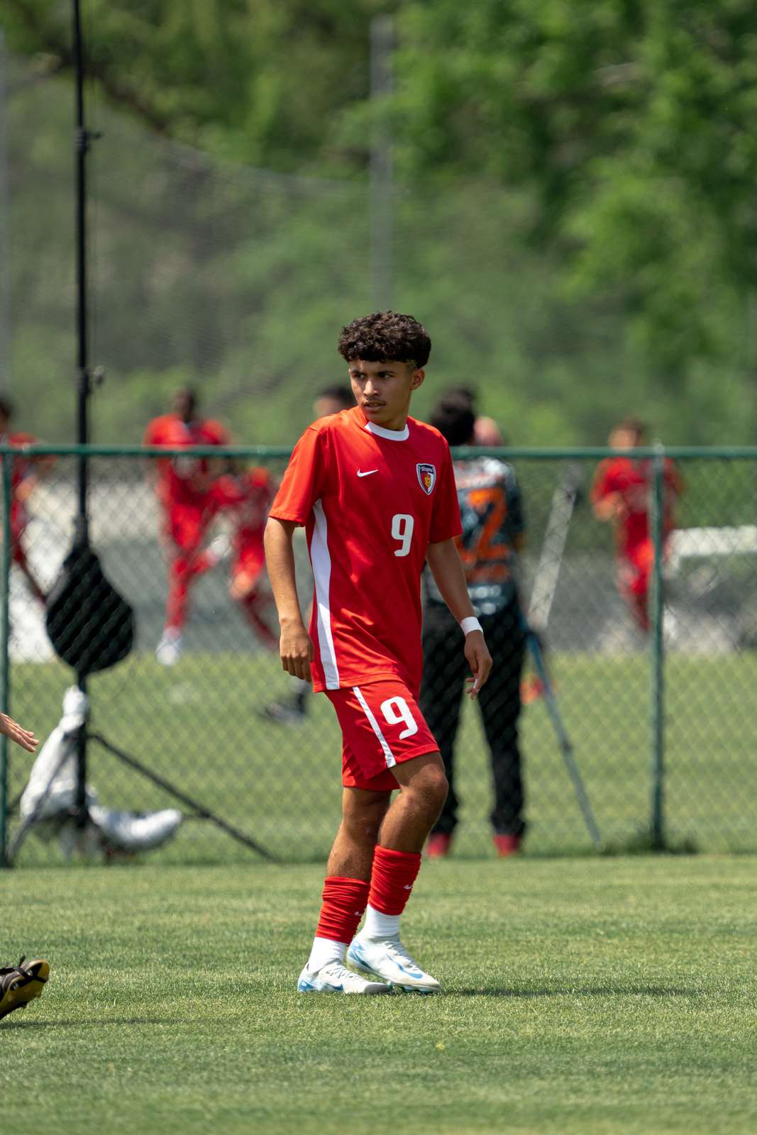 Youth soccer player in a red kit attacking down the wing