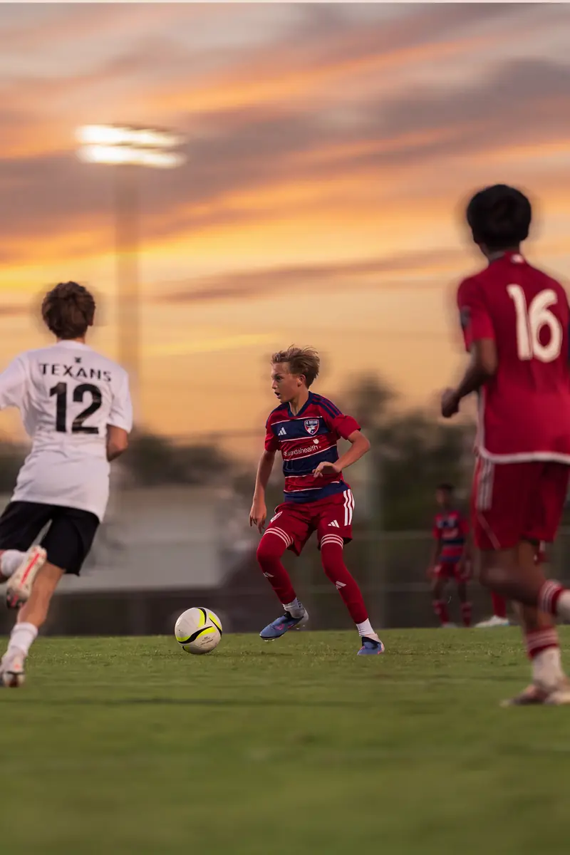 Youth soccer players chasing the ball under a Dallas sunset